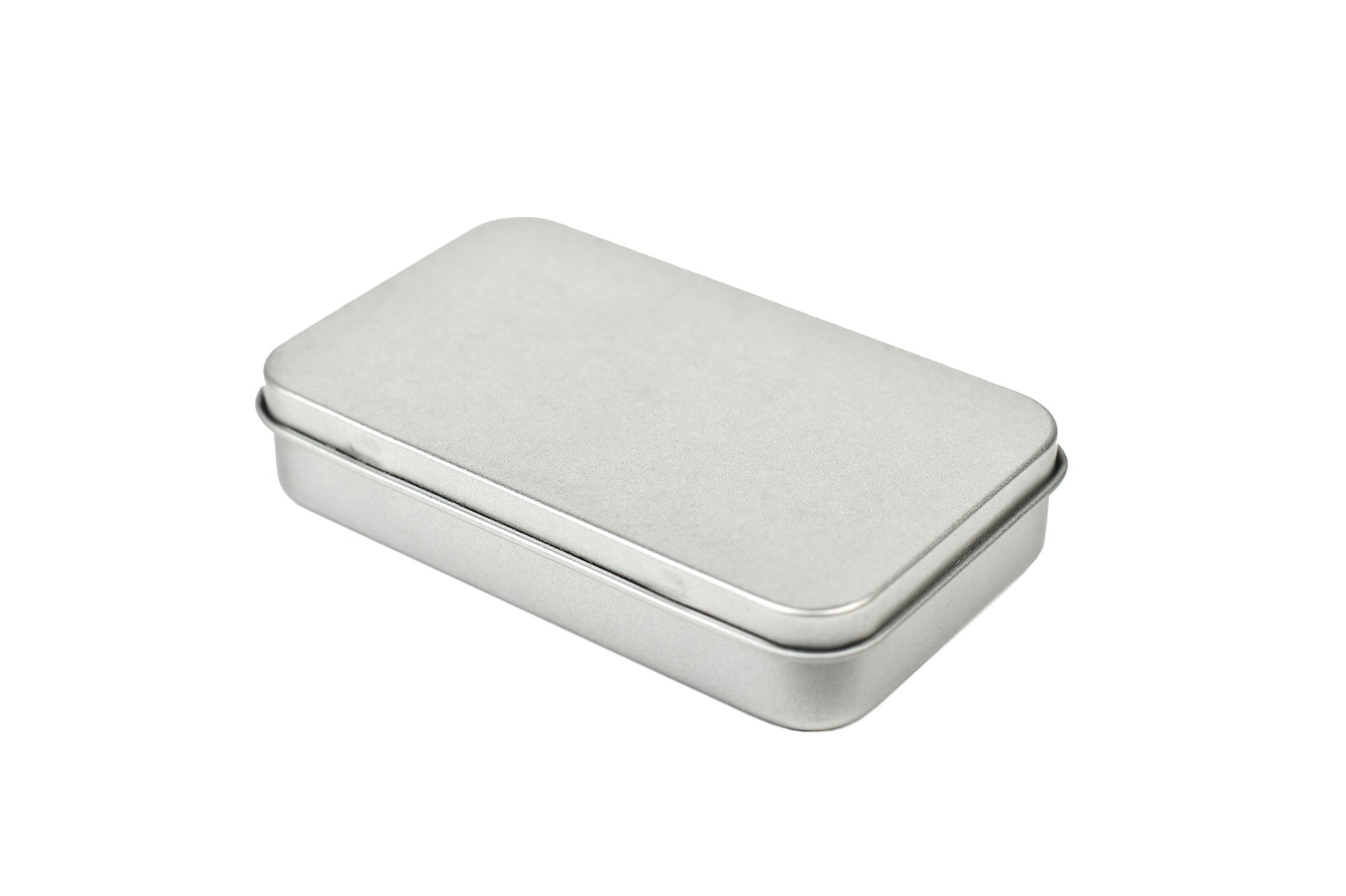 Flache, rechteckige Pocketdose aus silberfarbenem Metall mit aufgesetztem Klemmdeckel, geschlossen, vor weißem Hintergrund fotografiert.
